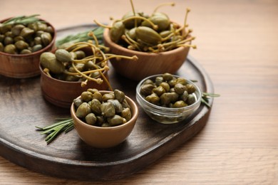 Photo of Delicious pickled capers and rosemary twigs on wooden table