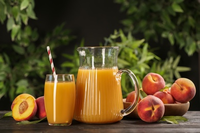 Photo of Natural peach juice and fresh fruits on wooden table