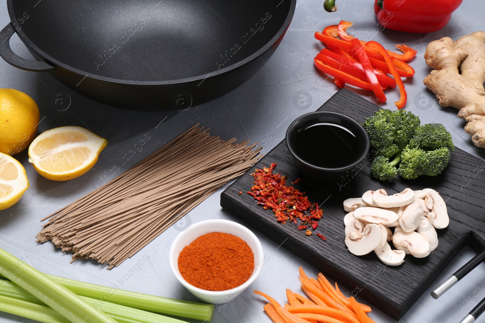 Photo of Wok and different products on grey table, closeup