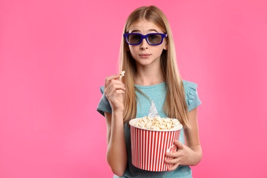 Photo of Emotional teenage girl with 3D glasses and popcorn during cinema show on color background