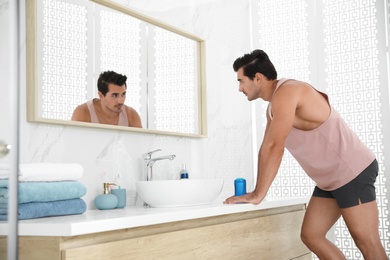 Photo of Handsome young man with deodorant in bathroom