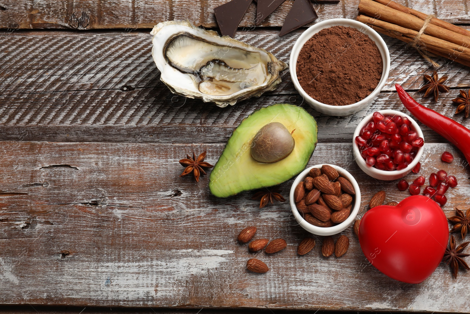 Photo of Natural aphrodisiac. Different food products and heart model on wooden table, flat lay. Space for text