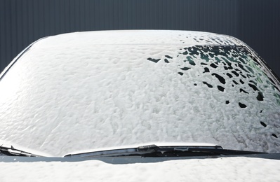 Automobile covered with foam at car wash, closeup of windshield