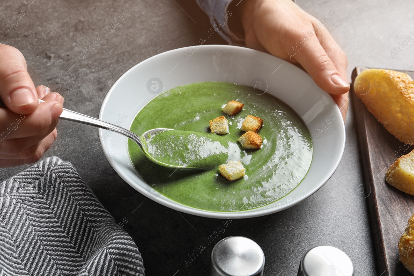 Photo of Woman eating fresh vegetable detox soup with croutons at table, closeup