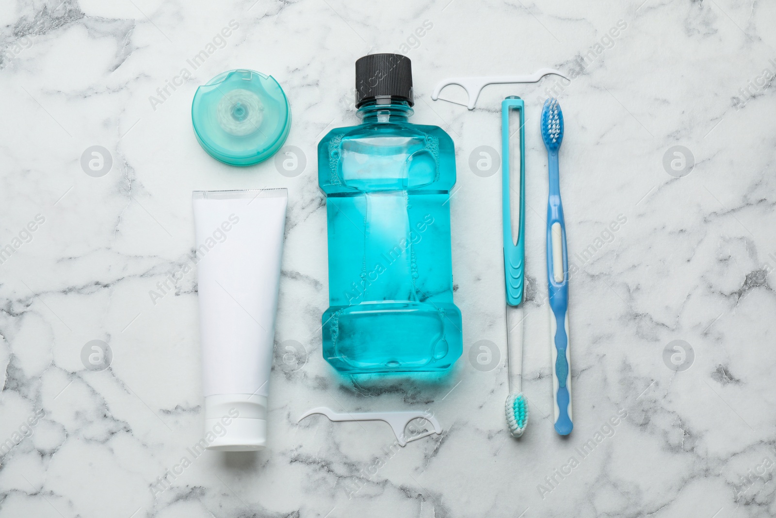 Photo of Flat lay composition with mouthwash and other oral hygiene products on white marble table