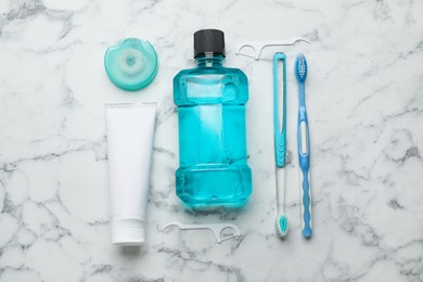 Photo of Flat lay composition with mouthwash and other oral hygiene products on white marble table