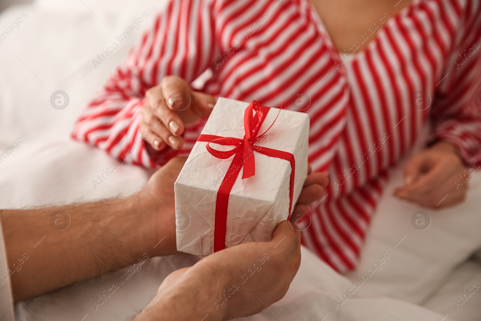 Photo of Lovely couple with gift box at home, closeup. Valentine's day celebration