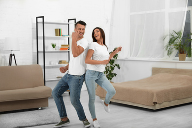 Happy young couple dancing together at home