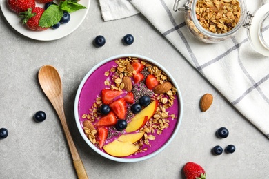 Delicious acai smoothie with granola and berries served on grey table, flat lay