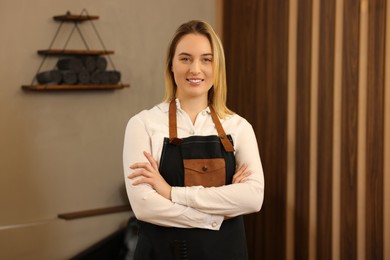 Portrait of professional hairdresser wearing apron in beauty salon