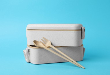 Photo of Bamboo lunch boxes and cutlery on light blue background. Conscious consumption