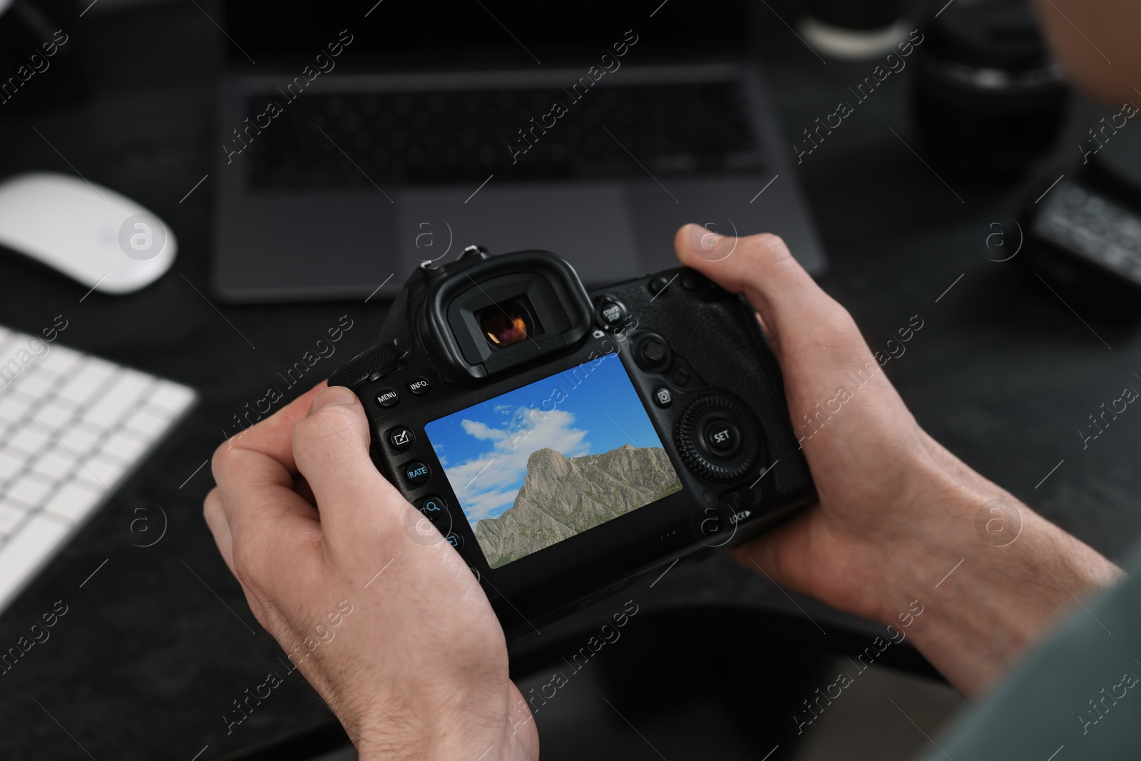 Image of Man with professional photo camera looking at shot of mountain indoors, closeup