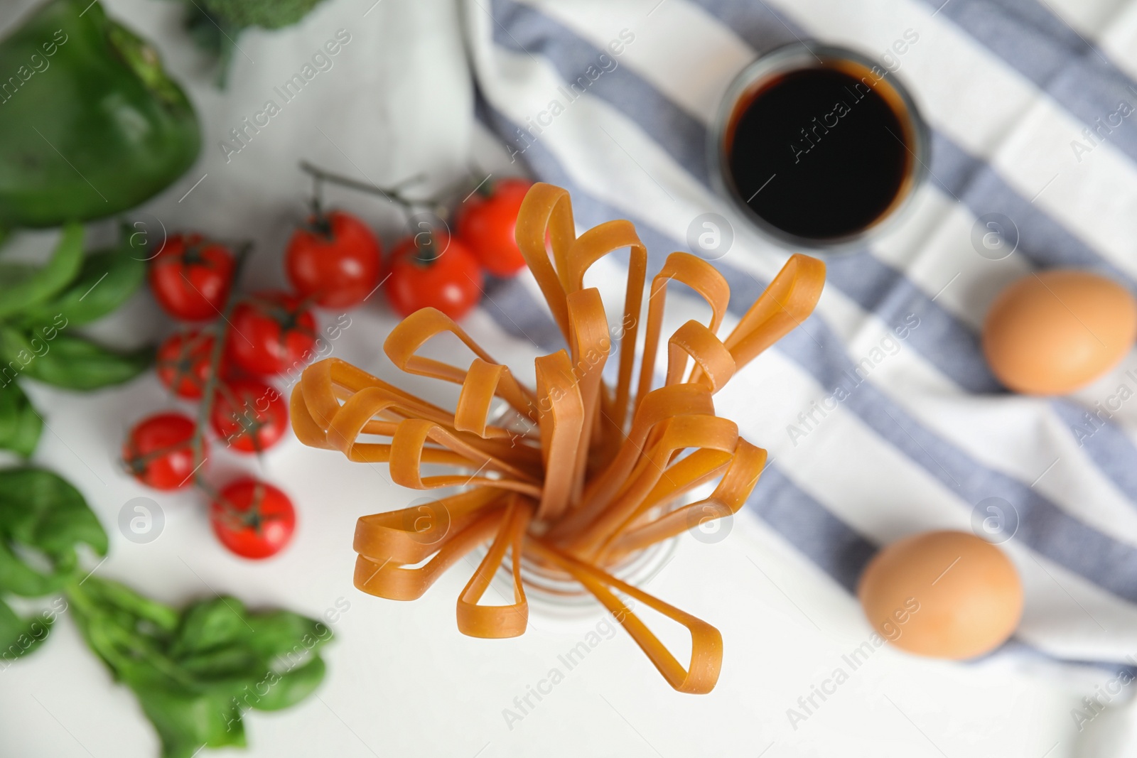 Photo of Uncooked buckwheat noodles and ingredients on white table, flat lay