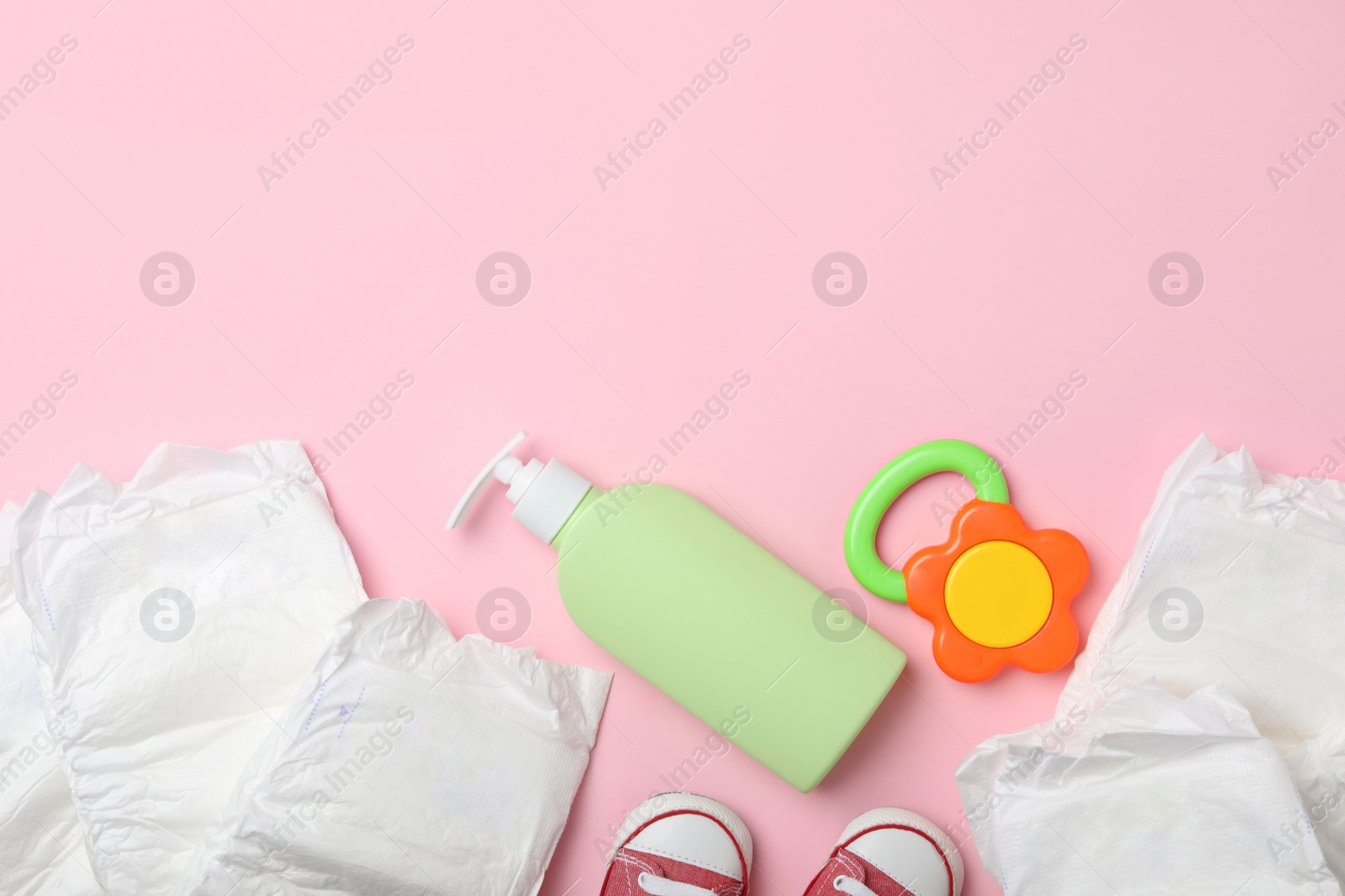 Photo of Diapers and baby accessories on pink background, flat lay. Space for text