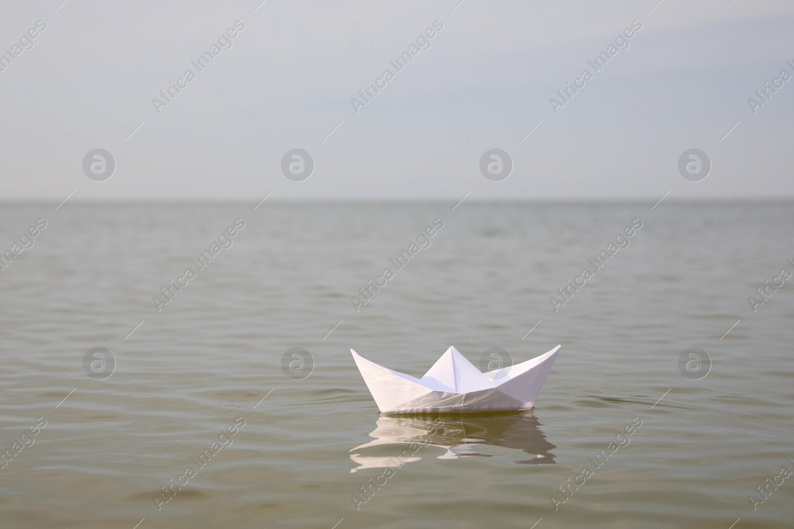 Photo of White paper boat on water surface, space for text