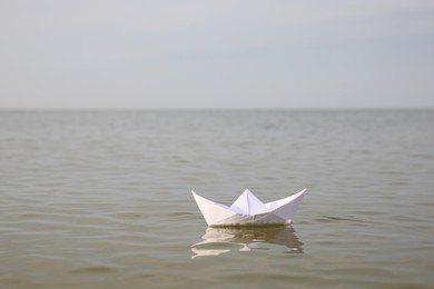 White paper boat on water surface, space for text