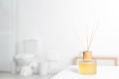 Photo of Reed air freshener with essential oils on table in bathroom. Space for text