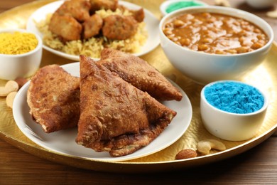 Traditional Indian food and color powders on wooden table, closeup. Holi festival celebration