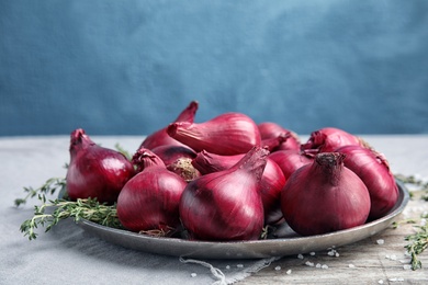 Plate with ripe red onions on table