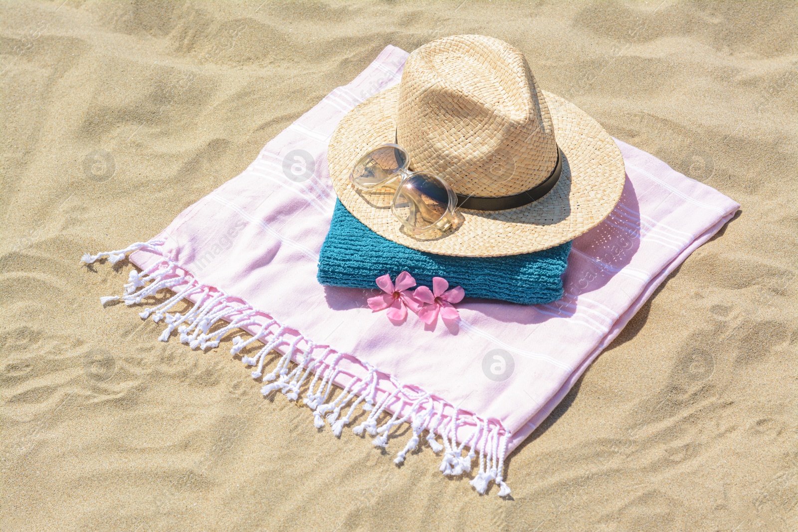 Photo of Stylish beach accessories and flowers on sand outdoors