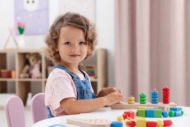 Photo of Motor skills development. Little girl playing with toys at table indoors