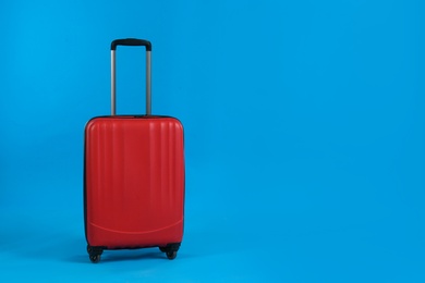 Photo of Red travel suitcase on light blue background, space for text. Summer vacation