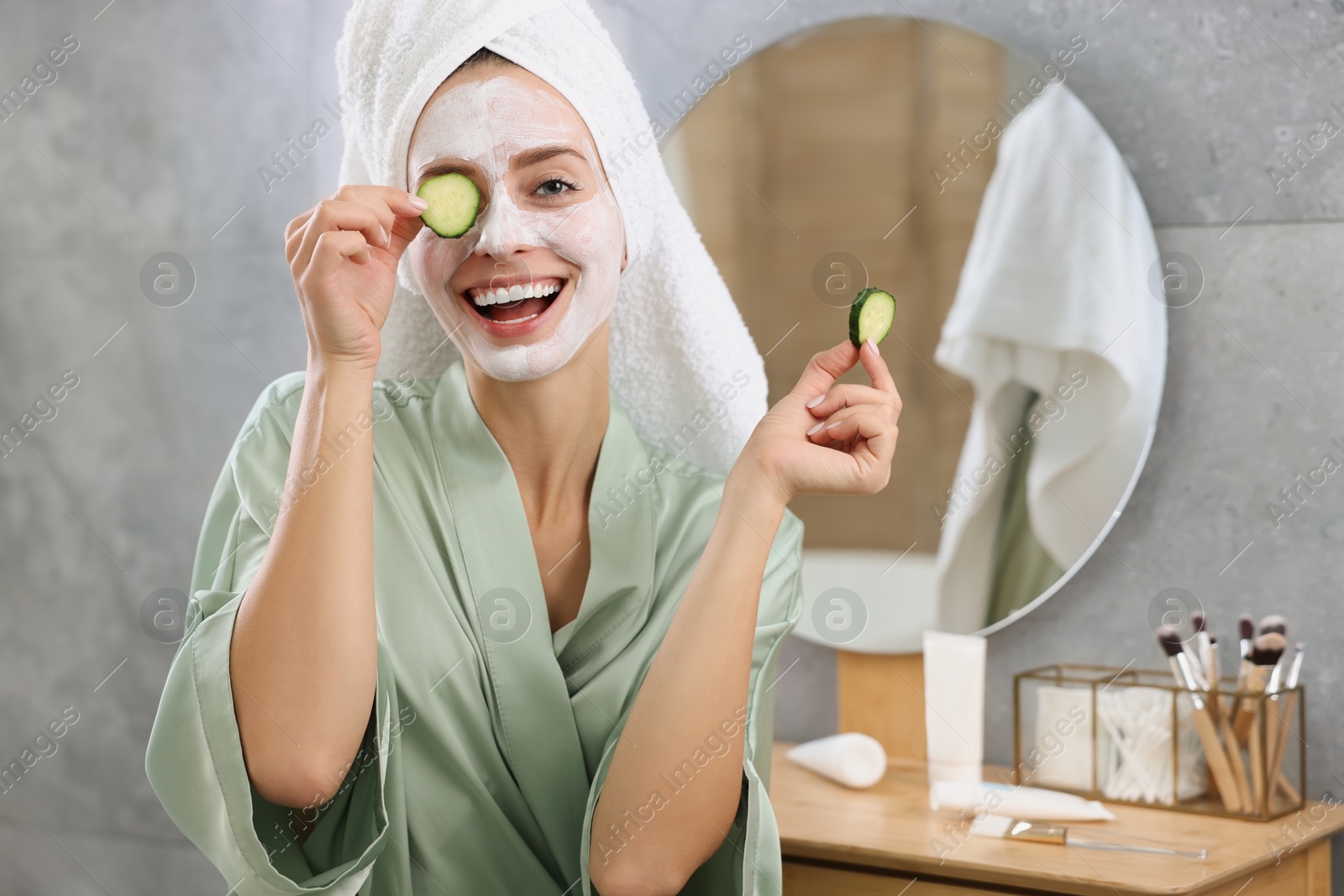 Photo of Woman with face mask and cucumber slices in bathroom, space for text. Spa treatments