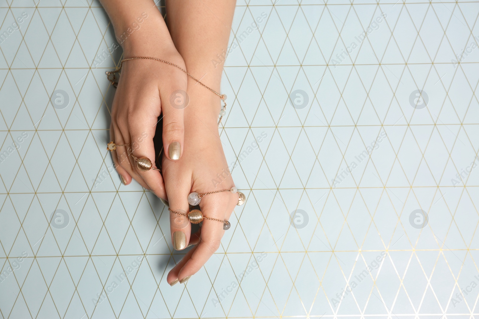 Photo of Woman with golden nail polish manicure on color background, top view. Space for text