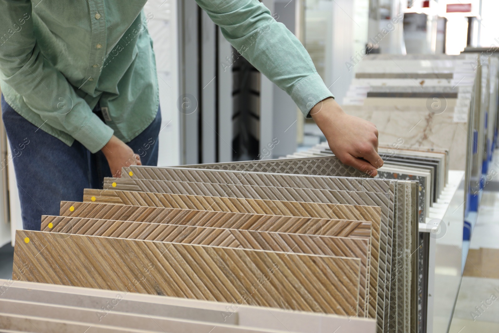 Photo of Man choosing tile among different samples in store, closeup