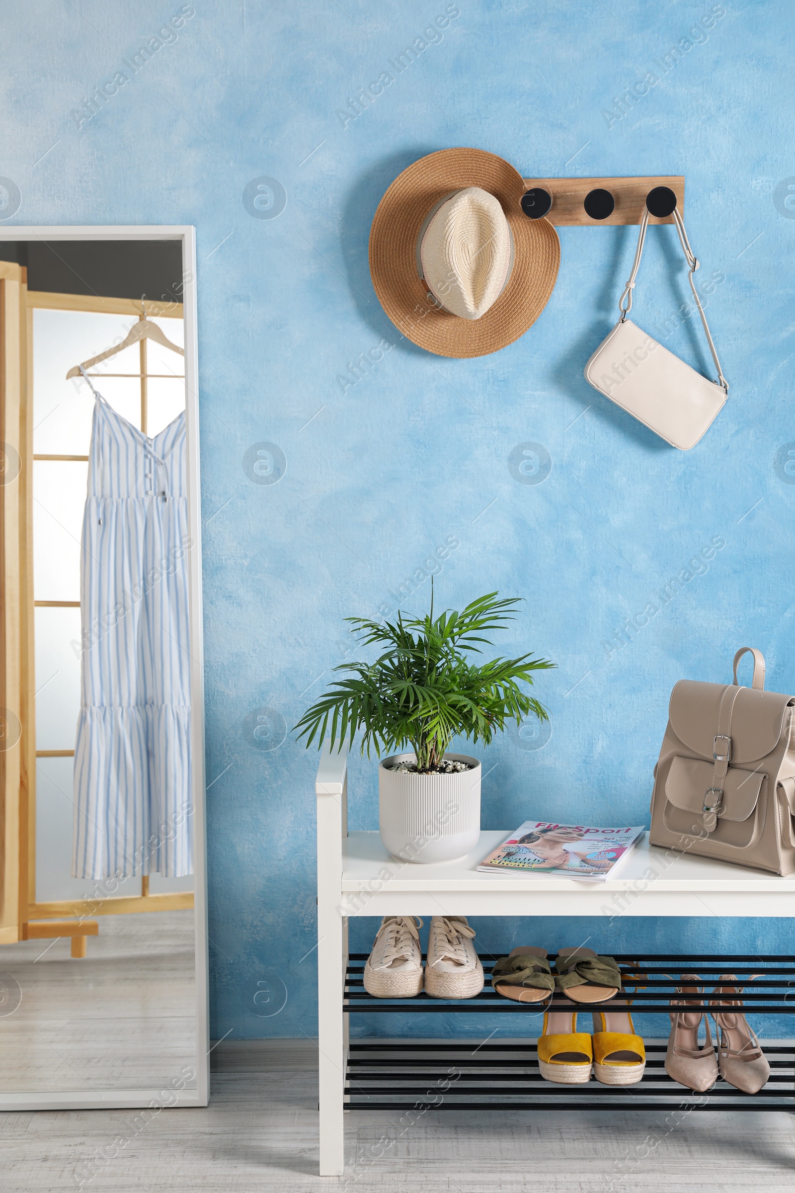 Photo of Stylish room interior with mirror, shoes and plant near light blue wall