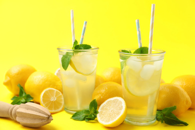 Photo of Natural freshly made lemonade with squeezer on yellow background. Summer refreshing drink