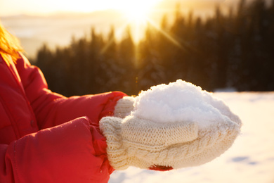 Photo of Woman holding pile of snow outdoors, closeup. Winter vacation