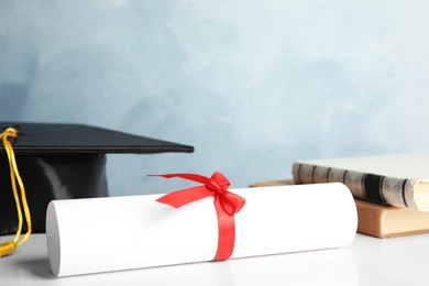 Photo of Student's graduation diploma on white wooden table against light blue background