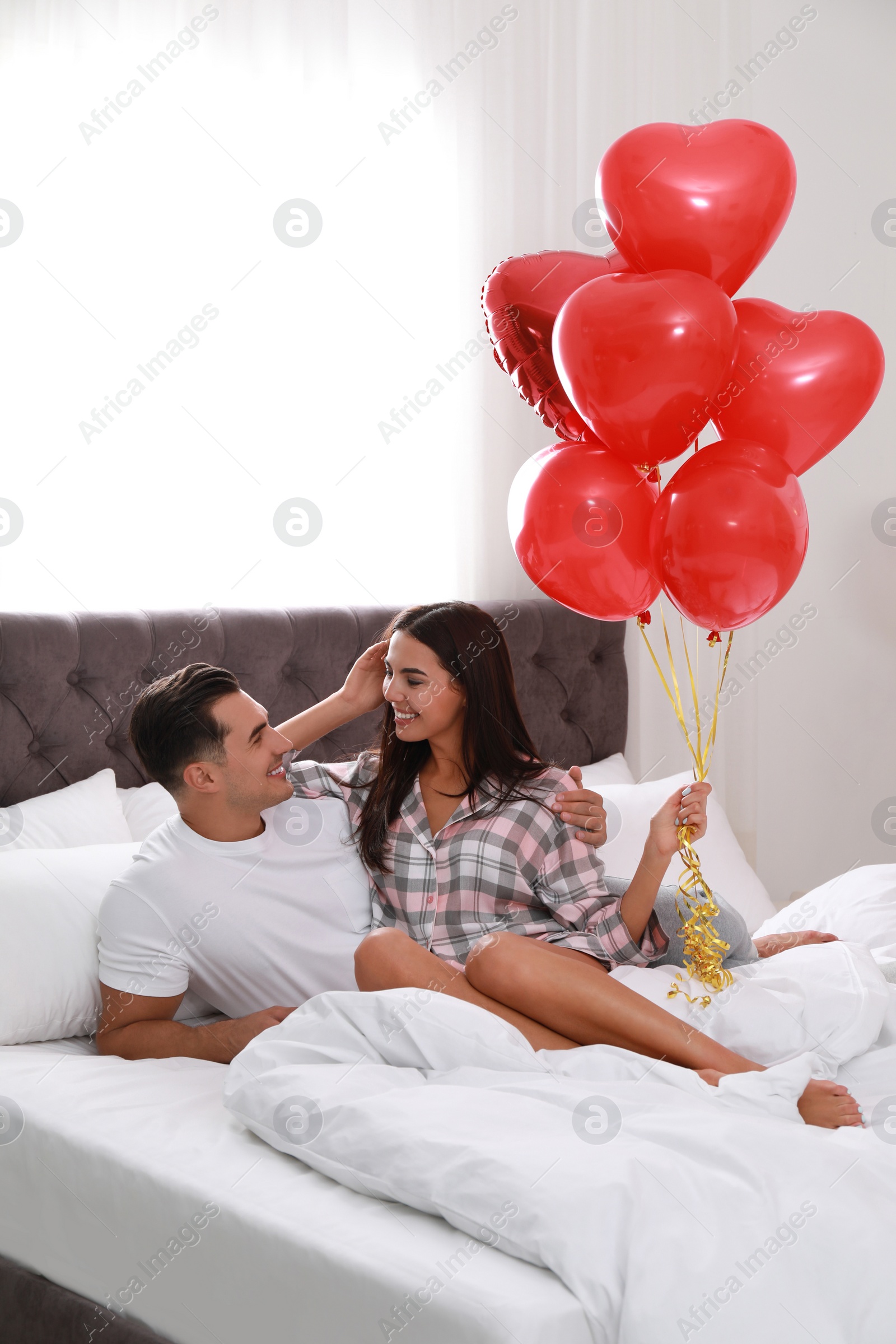 Photo of Beautiful couple with heart shaped balloons in bedroom