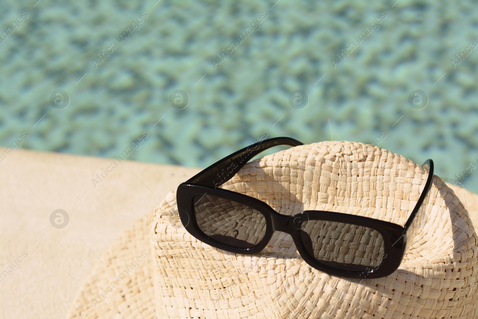 Photo of Stylish hat and sunglasses on blurred background, closeup