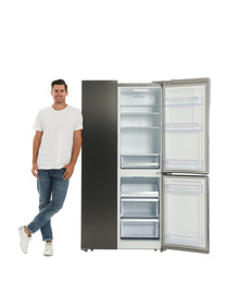 Photo of Man near open empty refrigerator on white background