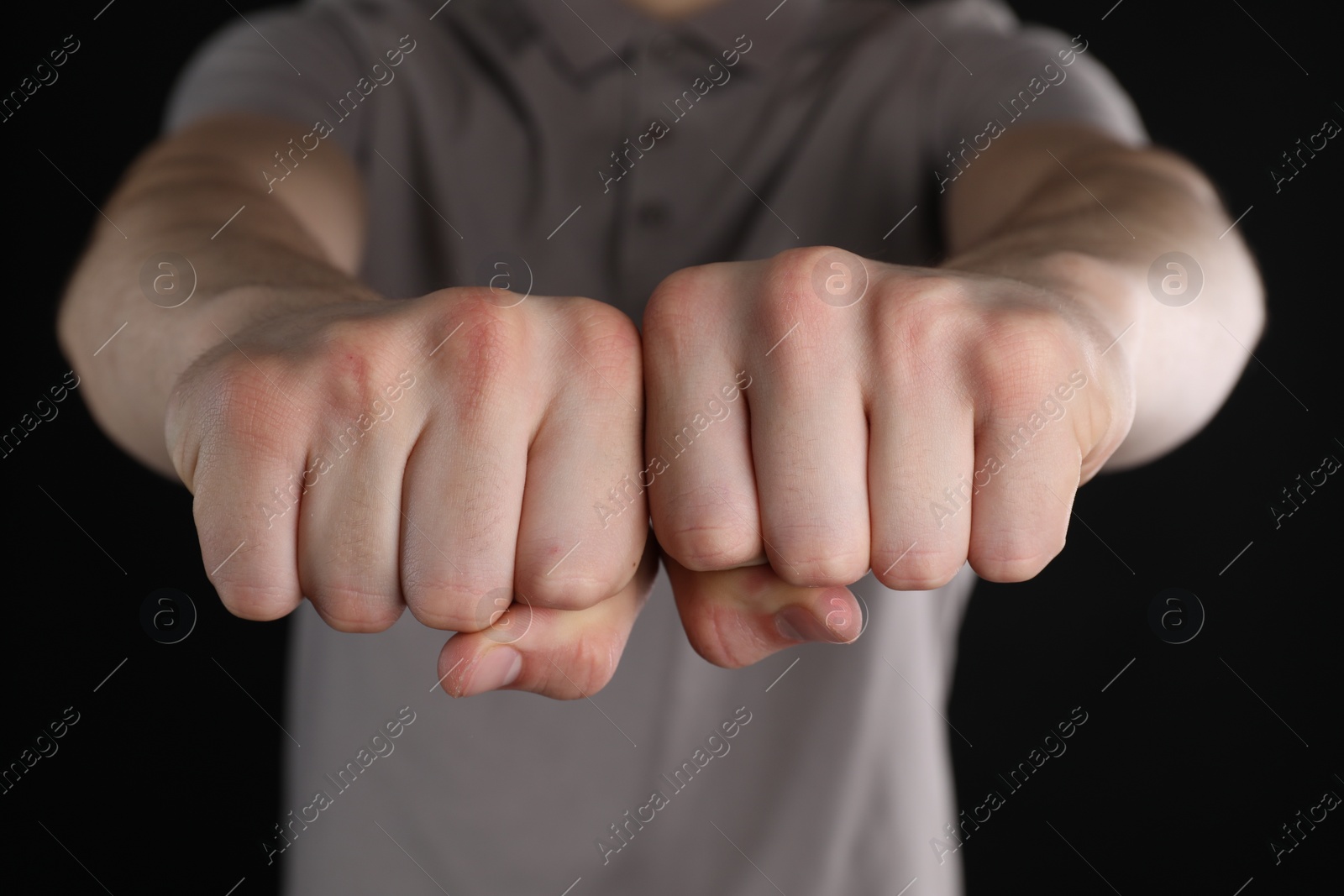 Photo of Man showing fists with space for tattoo on black background, closeup