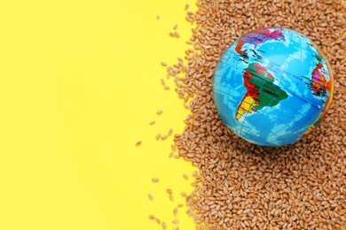 Photo of Import and export concept. Globe and wheat grains on yellow background, flat lay with space for text