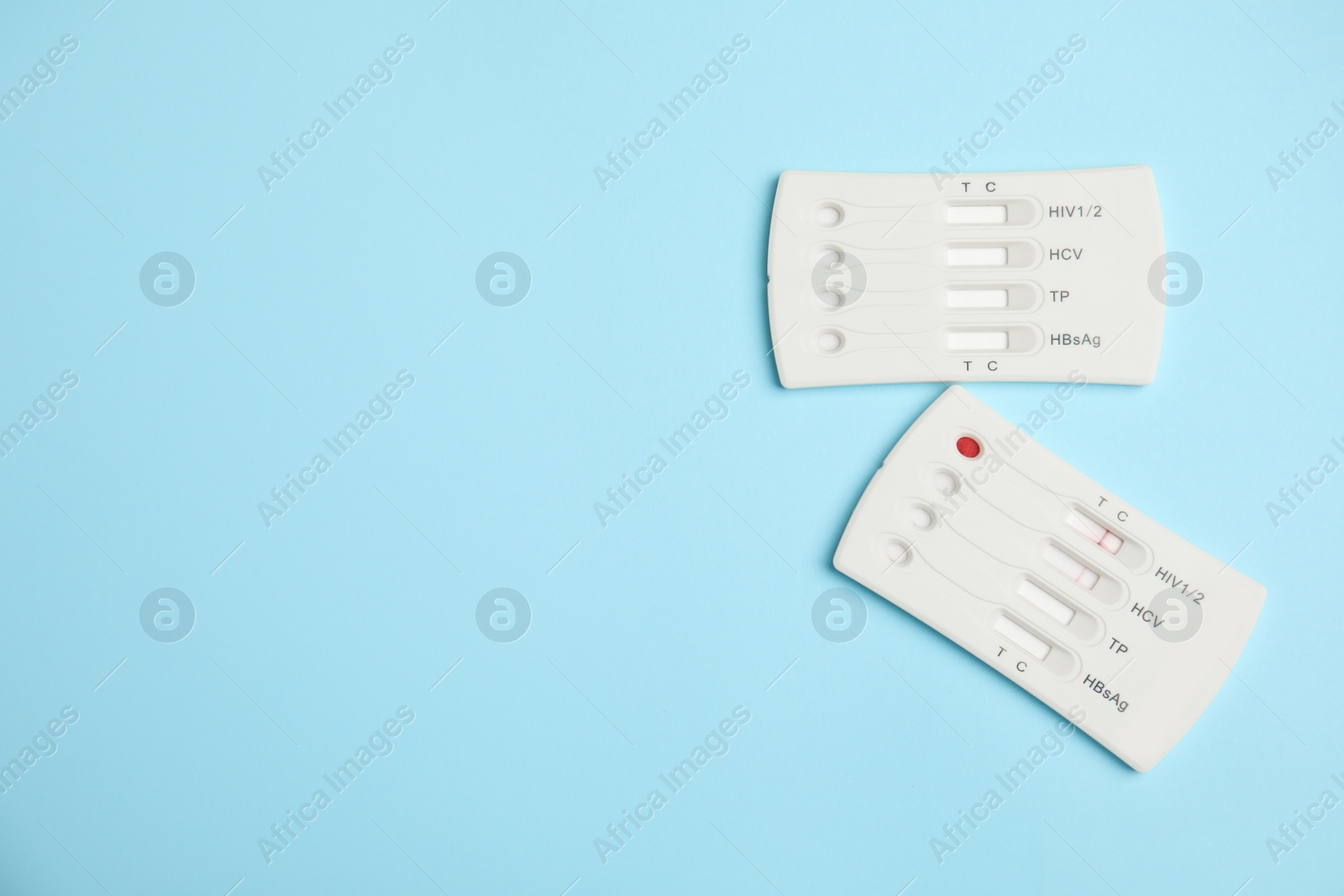 Photo of Two disposable express hepatitis tests on light blue background, flat lay. Space for text