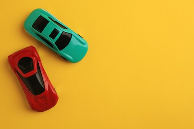 Photo of Bright cars on yellow background, flat lay with space for text. Children`s toys