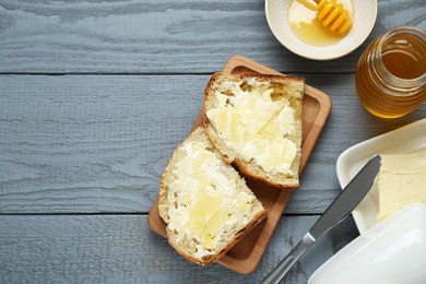 Slices of bread with butter and honey on grey wooden table, flat lay. Space for text
