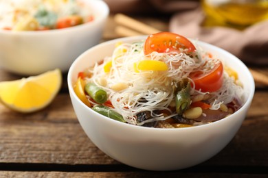 Tasty cooked rice noodles with vegetables on wooden table