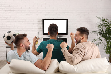 Photo of Group of friends watching football at home, back view