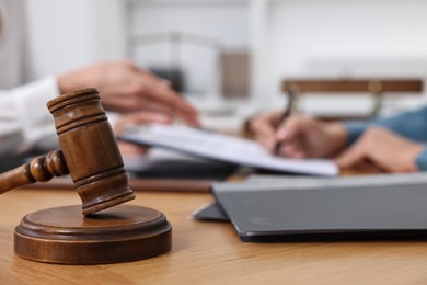 Photo of Senior woman signing document in lawyer's office, focus on gavel