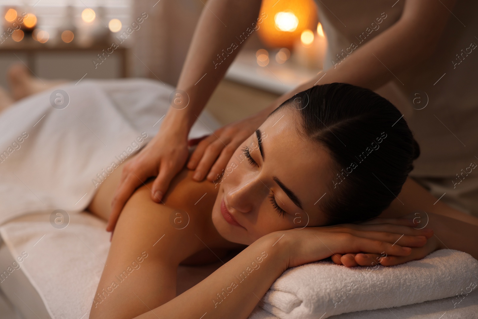 Photo of Woman receiving back massage on couch in spa salon