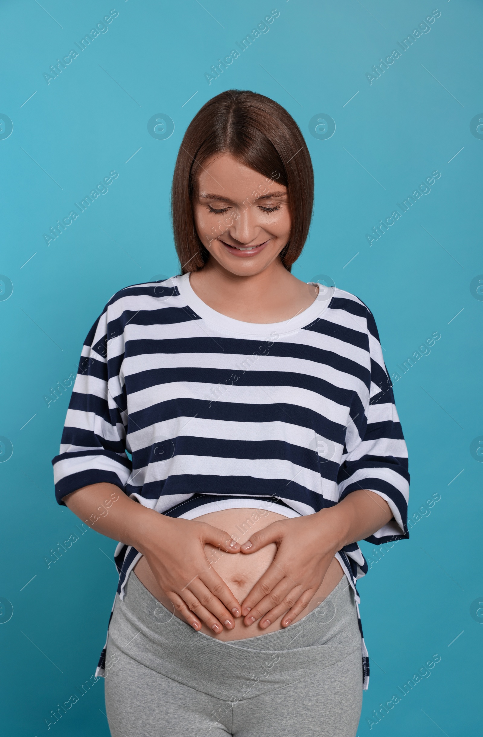 Photo of Happy young pregnant woman on light blue background