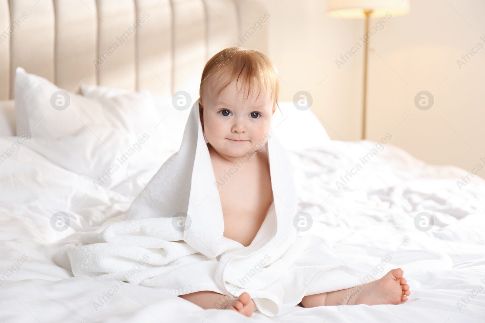 Photo of Cute little baby with soft towel on bed after bath