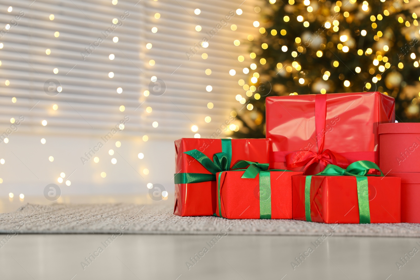 Photo of Beautifully wrapped Christmas gifts on rug indoors, space for text