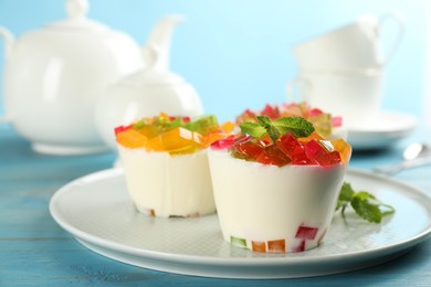 Delicious broken glass jelly dessert on light blue wooden table, space for text