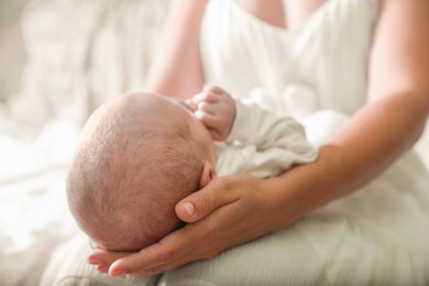 Photo of Mother holding newborn baby indoors, focus on head